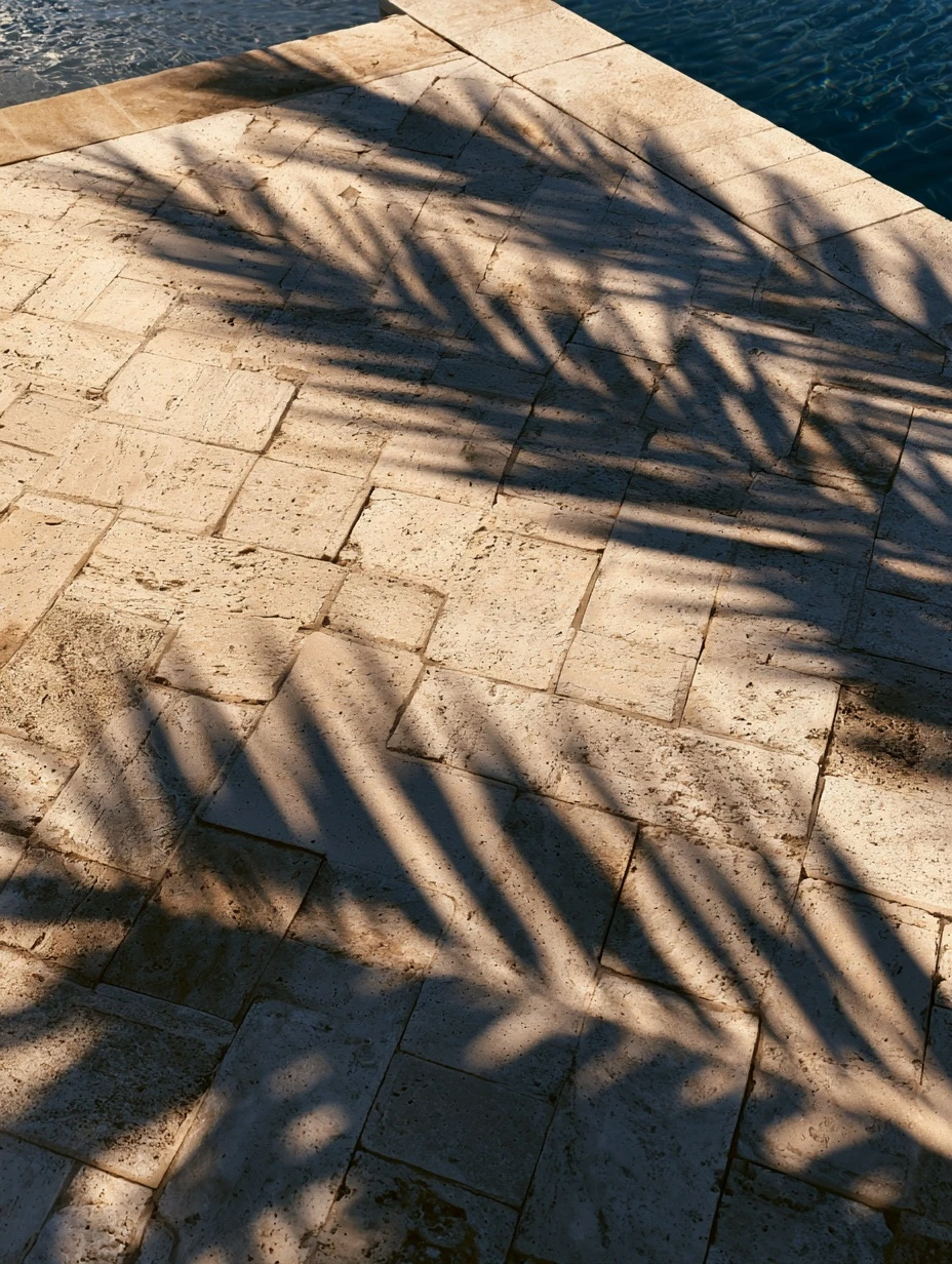 A herringbone paver pool deck beside a screened Southwest Florida pool in late afternoon light